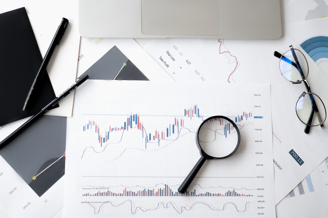 Data analysis chart with a magnifying glass on a desk, symbolizing predictive analytics and scenario modelling for smarter business decisions.