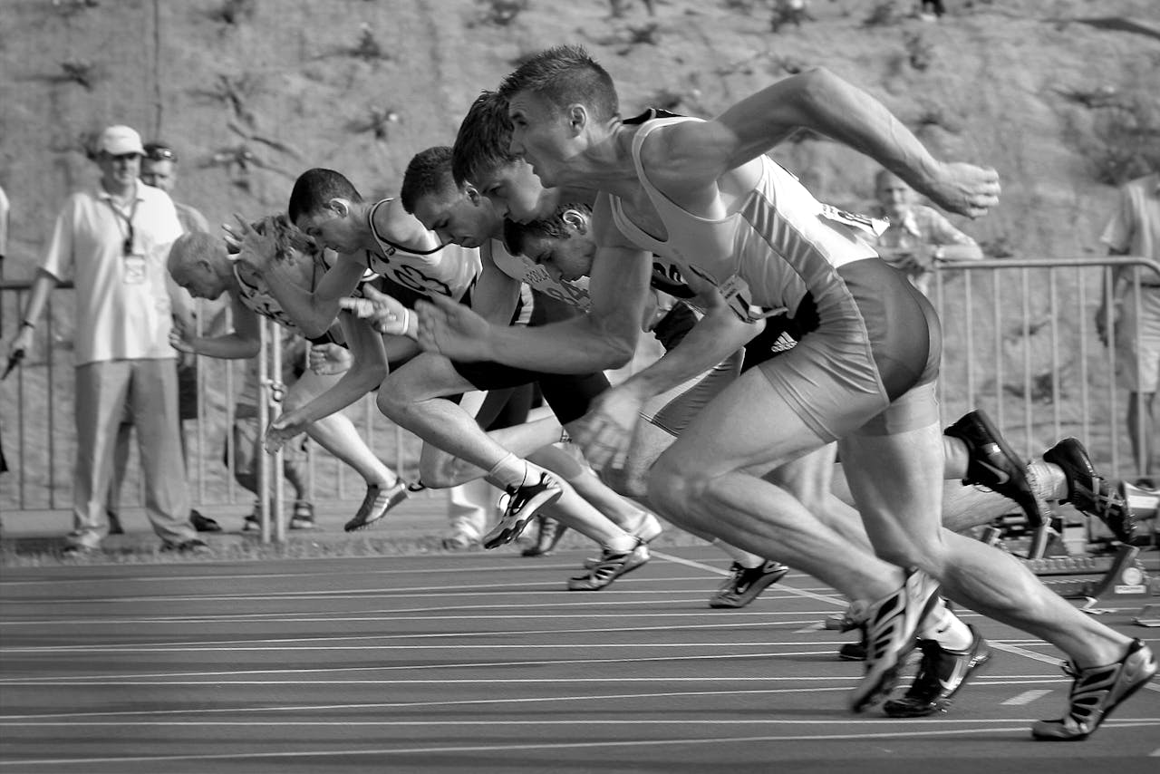 Athletes sprinting at the start of a race, symbolizing the need for speed and efficiency through automation of legacy systems in business operations.